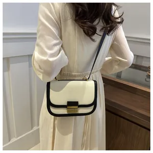 Detail of a beige canvas saddle bag with black leather trim and vintage gold metal clasp