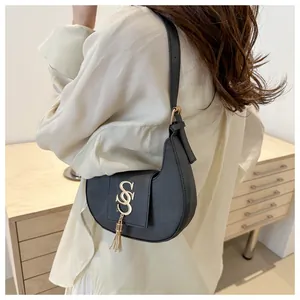 Vue détaillée du sac croissant noir avec boucle dorée et pampille porté par un mannequin