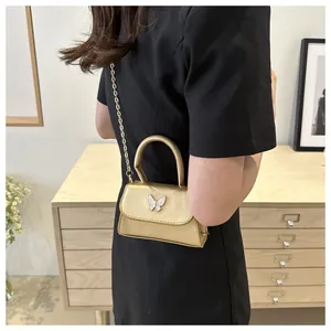 Vue détaillée du mini sac bandoulière doré champagne avec décoration papillon élégante