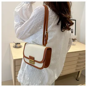 Detail of color-block saddle bag featuring canvas texture and vintage metal lock closure