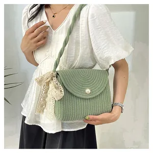 Detail of woven straw bag in green with lace bow and pearl button accent