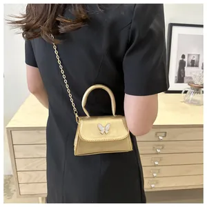 Gros plan détaillé d'un mini sac doré orné d'un papillon blanc avec une bandoulière chaîne