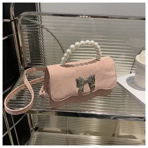 Detail of pink cloud-textured bag with pearl handle and silver bow decoration