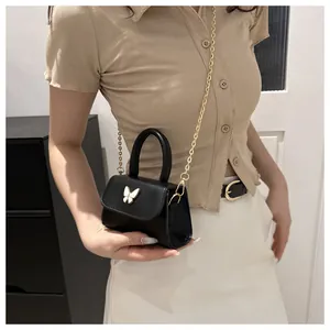 Vue détaillée du mini sac noir avec fermoir papillon doré et bandoulière en chaîne