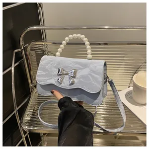 Macro detail of blue pleated texture bag with silver butterfly and pearl handle