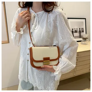 Detail showing color-block canvas saddle bag with leather trim and golden metal clasp