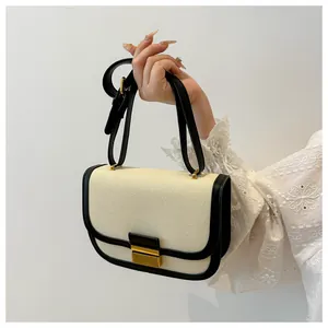 Close-up of golden rectangular clasp and contrast stitching on canvas saddle bag