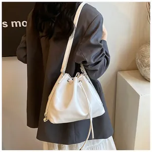 Rear view of a white drawstring bucket bag on a model in a minimalist modern setting