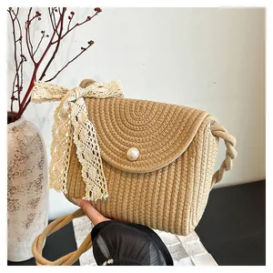 Detail view of woven straw crossbody bag featuring large pearl button and lace bow accent
