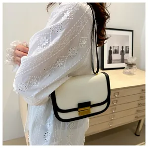 Detail of color-block saddle bag with gold metal buckle and black leather trim