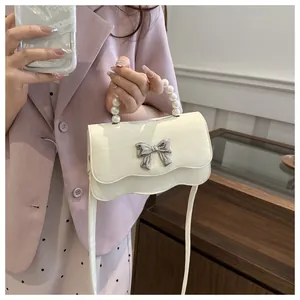 Detail of cream white leather bag with pearl handle and silver metal butterfly bow
