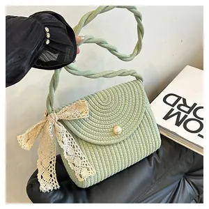 Detail of light green straw bag featuring a pearl clasp and delicate lace bow