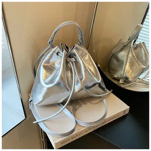 Detailed close-up of metallic silver drawstring bucket bag on a reflective surface