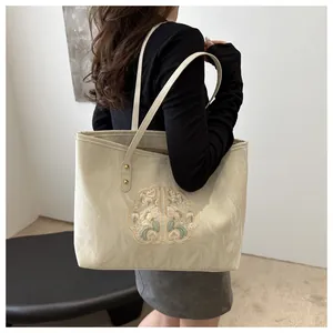 Détail de la broderie florale et de la texture plissée sur un sac cabas ivoire