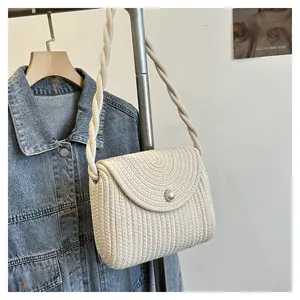 Detail of cream straw woven shoulder bag with pearl buckle and braided rope strap