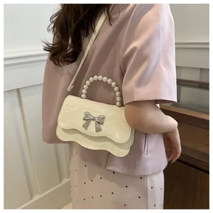 Detail of cream pleated crossbody bag with pearl handle and silver butterfly buckle