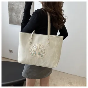 Détail de broderie chinoise élégante sur un sac fourre-tout en toile beige avec rivets dorés