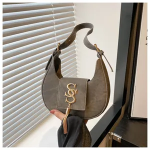 Détail du sac hobo gris avec une boucle dorée en S et des franges métalliques