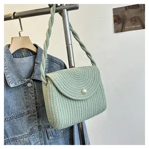 Detailed close-up of light green woven shoulder bag with pearl clasp and twisted strap