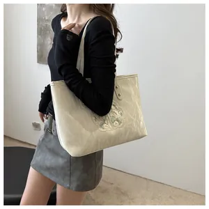 Gros plan d'un sac cabas en toile beige avec broderie florale chinoise et texture froissée