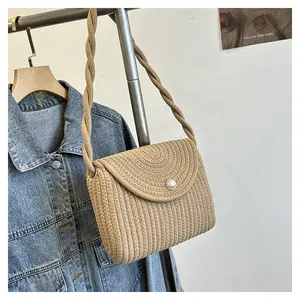 Detail of beige straw bag featuring a large pearl button closure and rope strap