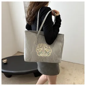 Gros plan d'un sac cabas gris texturé orné d'élégantes broderies florales chinoises traditionnelles