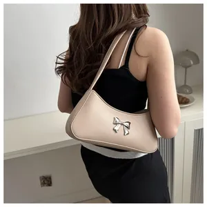Dettaglio borsa a mezzaluna beige con un fiocco metallico argentato decorativo