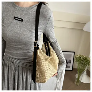 Detail of handwoven beige straw tote bag with thin black leather strap and gold buckle