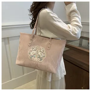 Détail de la broderie de lotus rose sur un sac en toile plissée de style néo-chinois