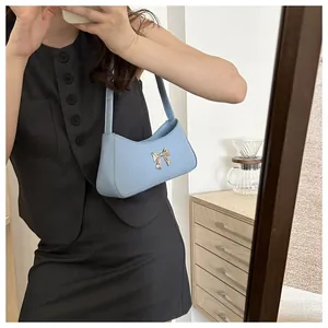 Selfie miroir montrant un sac bandoulière croissant bleu clair avec nœud doré