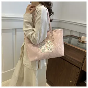 Détail du cabas rose clair avec broderie florale traditionnelle et texture plissée