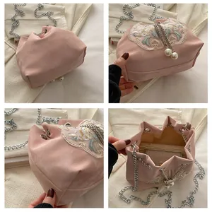 Détail du sac seau en velours rose avec broderie florale et bandoulière perle