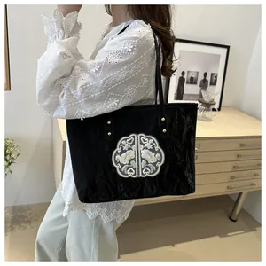 Détail de la broderie florale sur sac cabas en toile noire avec tissu plissé texturé