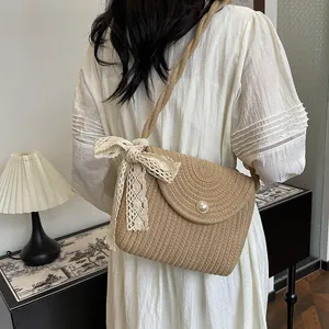 Straw shoulder bag with pearl button and lace ribbon detail in a rustic interior