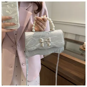 Close-up of pearl handle and silver butterfly buckle on grey pleated leather bag