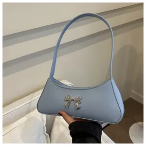 Dettaglio borsa a mezzaluna celeste con fiocco in metallo argento e finitura in pelle PU