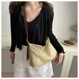 Detail of hand-woven straw tote bag with brown leather shoulder strap and metal buckle