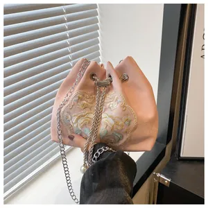Détail du sac seau en satin rose avec broderie florale et détails de perles au cordon