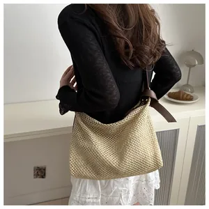 Close-up of the large woven tote bag featuring beige knit texture and brown leather strap