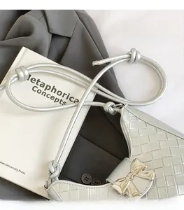 Detail of silver woven hobo bag with champagne gold bow and knotted thin shoulder strap