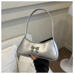 Dettaglio della borsa a mano argento metallizzato con fiocco in metallo 3D a mano