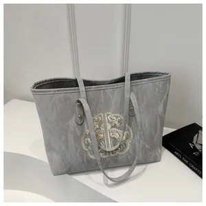 Détails de broderie sur sac cabas en toile gris clair avec rivets de style chinois