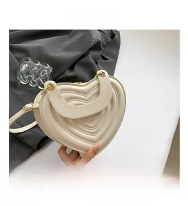 Detail view of heart-shaped quilted handbag in off-white PU leather with metal zipper
