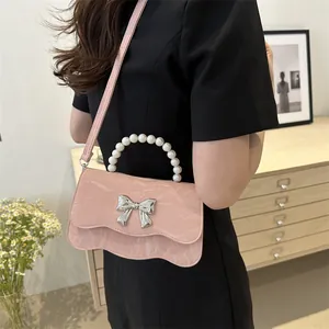 Pink pleated crossbody bag with pearl handle and silver butterfly buckle on black dress