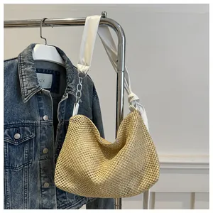 Detail of woven straw tote bag with white fabric strap and silver chain link
