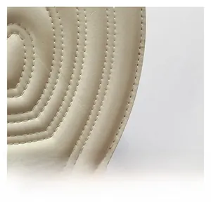 Close-up of cream leather bag featuring intricate curved stitching and premium texture