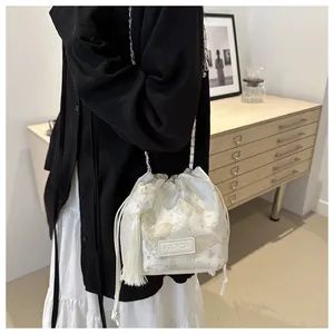 Detail der cremefarbenen Beuteltasche mit goldenem Schmetterlingsdruck und langen Fransen