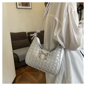 Detailed close-up of woven metallic silver shoulder bag with bow buckle and knotted strap