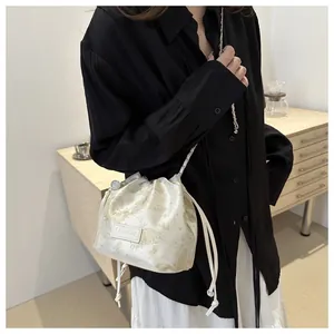 Detail der cremefarbenen Satin-Beuteltasche mit goldener Schmetterlingsstickerei
