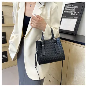 Detail of woven texture black handbag with handles and adjustable crossbody strap